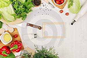 Healthy vegetarian ingredients for spring fresh green salad and kitchenware on white wood board, top view, copy space. Spring vita