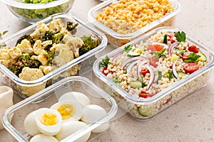 Healthy vegetarian meal prep with boiled eggs, roasted vegetables, cooked lentils, couscous salad and nuts