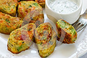 Healthy vegetarian potato patties with carrots, broccoli, bell pepper, green peas and onions with sour cream sauce with dill and