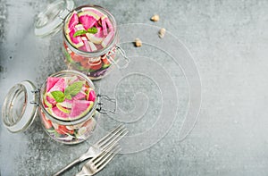 Healthy vegetarian salad in jars over grey concrete background