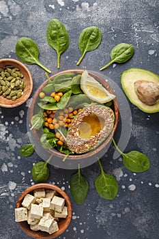 Flat lay of vegetarian salad with tofu, chickpea, avocado and sunflower seeds. Healthy vegan food concept. Dark background, top v