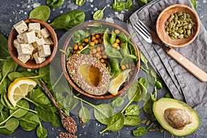 Healthy vegetarian salad with tofu, chickpea, avocado and sunflower seeds. Healthy vegan food concept. Dark background, top