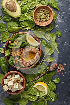 Flat lay of vegetarian salad with tofu, chickpea, avocado and sunflower seeds. Healthy vegan food concept. Dark background, top v