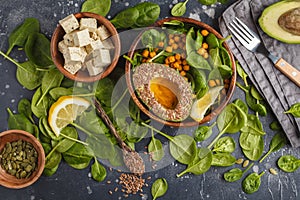 Flat lay of vegetarian salad with tofu, chickpea, avocado and sunflower seeds. Healthy vegan food concept. Dark background, top v