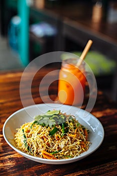 Healthy Vegetarian vegan menu Delicious Singapore style Stir fried rice noodles with carrot orange smoothies on wooden table in