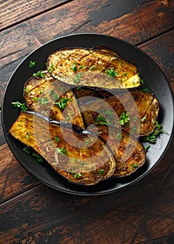 Healthy vegeterain Oven baked aubergines, Eggplant with parsley and herbs in a black plate