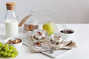 Healthy, vegeterian fiber food. Fruits, almond milk, honey granola in jars with flax seeds, cranberries, coconut, yogurt and