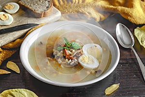 Healthy and warming winter soup with rice, carrot, chickpeas, chicken, ham and boiled egg over rustic wooden table background