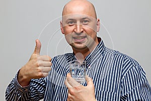 Healthy Water A young man drinking water out of a glass. He shows the thumb up sign