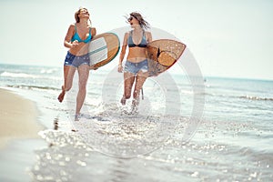 Healthy  watersports at summer vataion.  Girls with  surfboard walking at beach photo