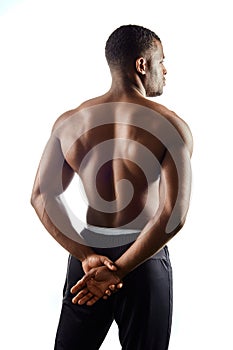 Healthy well-built afro man with hands on his back posing to the camera.