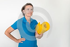 Healthy white fit smiling happy senior woman stand and hold mat in hands, life is good