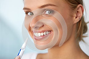 Healthy White Teeth. Beautiful Smiling Woman Using Whitening Pen