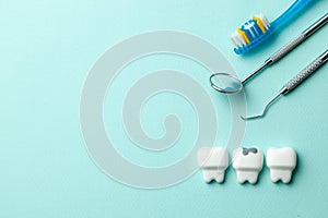 Healthy white teeth and tooth with caries on green mint background. Toothbrush and dentist tools mirror, hook. Copy space for text