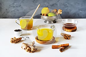 Healthy winter beverage with ginger, turmeric, cinnamon stick, lemon, honey and black pepper