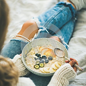 Woman in jeans and sweater eating vegan breakfast, square crop