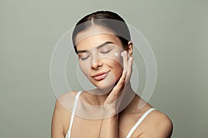 Healthy woman applying moisturize cream on her face. Facial treatment and healthcare concept photo