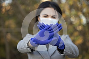 Healthy woman in blue medical protective mask showing gesture stop.