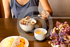 Healthy woman eating corn flakes cereal and coffee for breakfast on table.