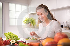 Healthy woman eating salad in the kitchen