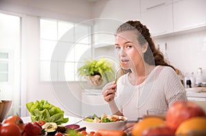 Healthy woman eating salad in the kitchen