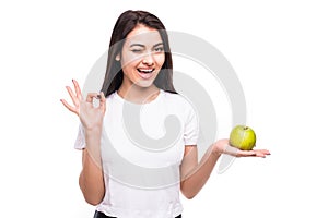 Healthy woman giving ok hand gesture with green apple on white background