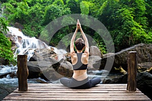 Healthy woman lifestyle balanced practicing meditate and zen energy yoga on the bridge in morning the waterfall in nature forest. photo