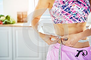 Healthy woman measuring her waist with tape