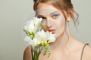 Healthy woman with natural clear skin with freckles holding white flowers