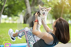 A healthy woman playing with a corgi puppy while excersing on yo