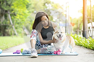 A healthy woman playing with a corgi puppy while exercising