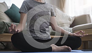 Healthy woman practicing yoga at home, sitting in lotus pose to meditation. Healthy lifestyle, meditation concept