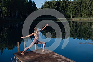 Healthy woman practicing yoga on the lake at sunrise enjoying positive energies from nature