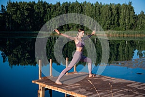 Healthy woman practicing yoga on the lake at sunrise enjoying positive energies from nature