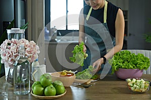 Healthy woman preparing ingredients for making a fresh vegetable salad.