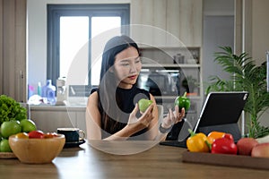 Healthy woman preparing vegetable salad using digital tablet for recipes online