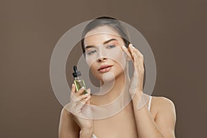 Healthy woman spa model with cosmetic oil on brown background. Facial treatment, body care and alternative medicine concept