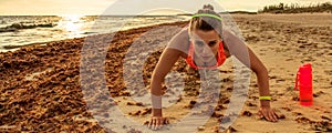 Healthy woman in sport clothes on beach doing pushups