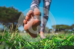 Healthy woman walking barefoot on green grass in summer. Closeup of woman feet walking on the ground and exercise