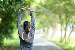 Healthy woman warming up stretching her arms. Asian runner woman workout before fitness and jogging session on the road nature par