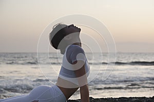 Healthy with Yoga Concept.  Attractive young woman practice Cobra Pose on the beach during sunset.