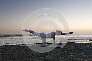 Healthy with Yoga Concept. Attractive young woman practice yoga on the beach during sunset.