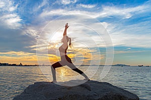 Healthy yoga woman lifestyle exercising vital meditate and energy yoga on the rock near the seashore,