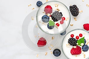 Healthy yogurt with fresh forest berries in glasses on white marble background. healthy diet breakfast