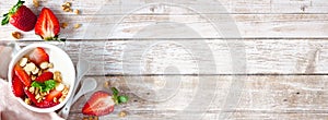 Healthy yogurt with fresh strawberries and granola, banner with corner border against a rustic wood background with copy space