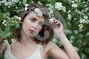 Healthy young adult woman female model with clean fresh skin, make-up and brown hair in blossom garden on green leaves background