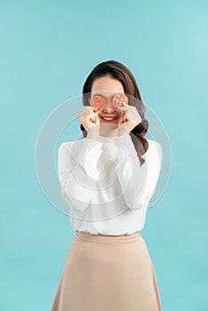 Healthy young Asian woman holding fresh tomato slice over blue isolated background. Healthy and beauty skin care concept