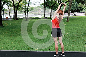 Healthy young Asian woman stretching her hands before run in park in morning. Workout and exercise concept