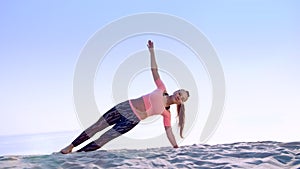 Healthy, young beautiful woman doing exercises for oblique abdominal press muscles,, on the beach, at sunrise, Makes
