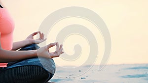Healthy, young beautiful woman meditating, practicing yoga on the beach, by the sea, at sunrise, Relaxes muscles, mind